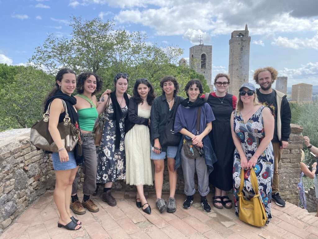 A group of nine people taking a picture in front of San Gimignano's towers, near Siena. The photo is being shown to participants to study abroad fairs across the US.