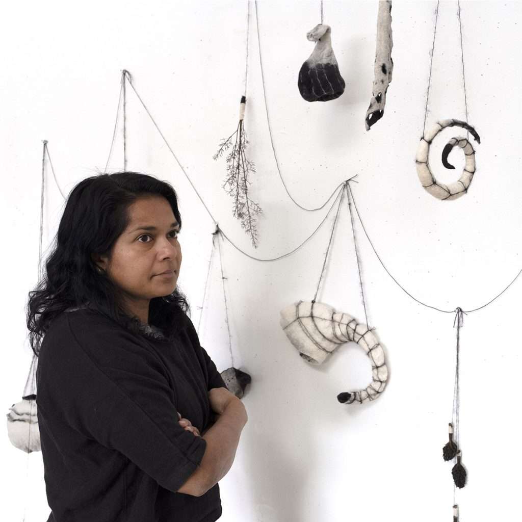 Photo of the artist Ruth Jeyaveeran with her work
